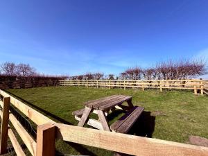 a wooden picnic table sitting next to a fence at Pond Cottage in Alnwick