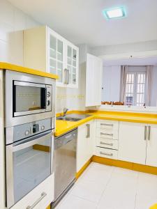 a large kitchen with white cabinets and a microwave at La Casita Gaditana Centro in Cádiz