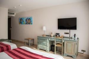 a bedroom with a desk with a television on the wall at Logis Le Saint Nicolas in Bar-sur-Aube