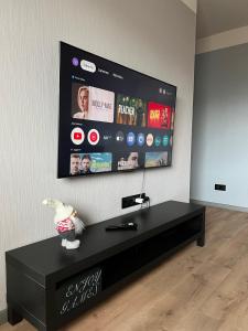 a black entertainment center with a flat screen tv on a wall at Mare et Ventus in Ventspils