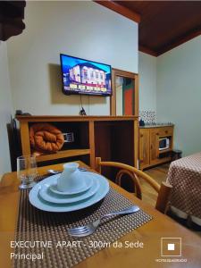 ein Esszimmer mit einem Tisch und einem Fernseher in der Unterkunft San Diego Suítes Hotel Quadrado in Santa Bárbara