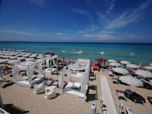 einen Strand mit weißen Sonnenschirmen und Stühlen sowie das Meer in der Unterkunft Villetta mare blu Baia Verde in Gallipoli