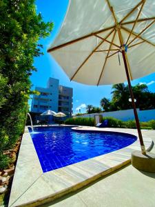 an umbrella sitting next to a swimming pool at Flat premium centro de Porto de Galinhas-Makambira Residence-Flat309 in Porto De Galinhas