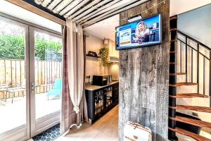 a living room with a television on a wall at La Petite Escapade, maison avec jacuzzi privatif in Héricy