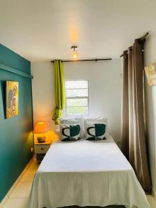 a bedroom with a white bed with a window at Appartement confortable à Fort-de-France, 45 m² avec terrasse in Fort-de-France