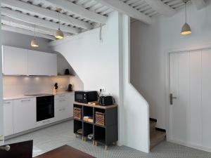a kitchen with white cabinets and black appliances at Apt Es Poal - Des Puig in Cadaqués