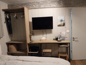 een slaapkamer met een bureau en een televisie aan de muur bij La petite cabane du pecheur in Honfleur