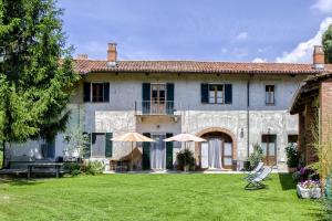 une grande maison en pierre avec des parasols dans la cour dans l'établissement B&B Cascina Moncrava, à Ivrea