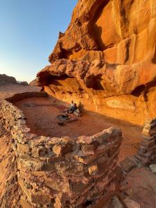a person sitting on a rock wall in the desert at Wadi Rum Paris Cave in Wadi Rum +17 photos