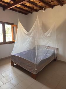 a bed with a mosquito net hanging from the ceiling at Stash House in Cap Skirring