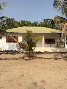 a white house with a palm tree in front of it at Stash House in Cap Skirring