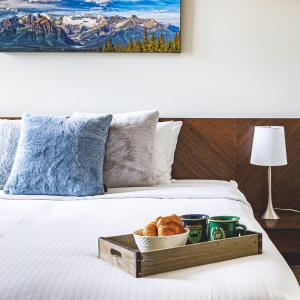 a tray of croissants and cups on a bed at Mountain Luxe in Canmore