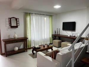 a living room with a couch and a tv at Casa Tororão - Arraial d'Ajuda in Porto Seguro