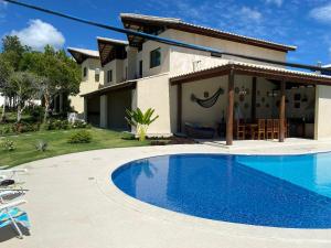 a villa with a swimming pool in front of a house at Casa Tororão - Arraial d'Ajuda in Porto Seguro