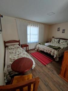 a bedroom with two beds and a table and a window at Pousada Charme Tiradentes in Tiradentes