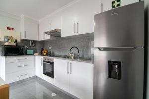 a kitchen with white cabinets and a stainless steel refrigerator at Natural Living Vacations in Furnas