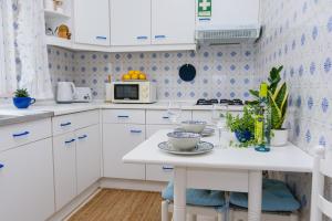 a kitchen with white cabinets and a white table with dishes at Hillside Studio with Sea View & Fibre Internet in Albufeira