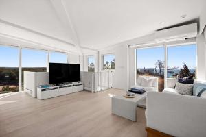 a living room with white furniture and large windows at Waterfront Hot Tub Sauna Private Beach in Wellfleet