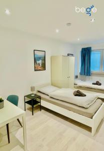 a bedroom with two beds and a desk and a table at BEGE APARTMENTS Rent & Repeat in Mettmann