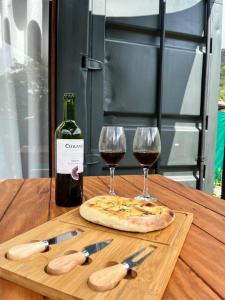 a wooden table with two glasses of wine and a pizza at Cabana ECO - Teresópolis in Teresópolis