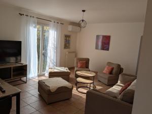 Una sala de estar con un sofá y sillas y un televisor. en Entre plage et vignobles Maison trois chambres, en Saint-Cyr-sur-Mer