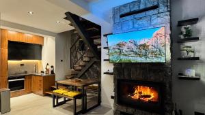 a living room with a fireplace and a tv on a wall at Durmitor Summit in Žabljak