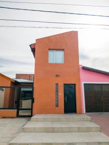 - un bâtiment orange avec deux portes et quelques marches dans l'établissement Departamento Lionel, à Río Gallegos