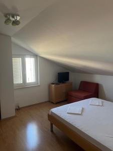 a bedroom with a bed and a red chair at Lavanda Apartments in Pakoštane