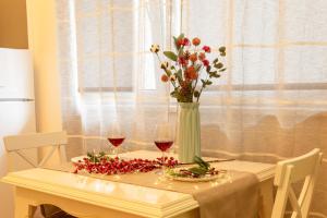 einen Tisch mit einer Vase Blumen und zwei Gläsern Wein in der Unterkunft Spacious Studio Close to City Center l Washing Machine l Kitchen in Novi Sad
