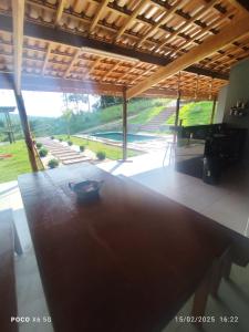 a room with a table and a view of a yard at Chácara Morada do Sol Ibiúna in Ibiúna