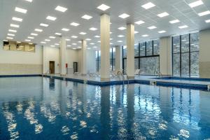 迪利然Ani Forest Hills Hotel and Resort, Dilijan的建筑物内蓝色水的游泳池