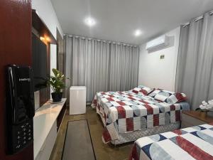 a hotel room with two beds and a television at Studio Sol - 3 min do Mossoró Cidade Junina in Mossoró
