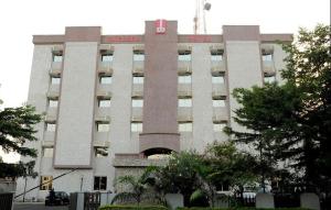 a large white building with a red sign on it at OFAS Chelsea Hotel in Abuja
