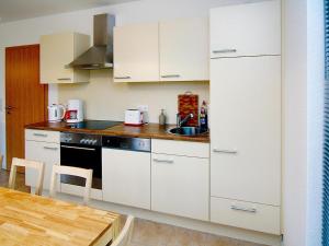 a kitchen with white cabinets and a sink and a table at Ferienhaus Kiebitz, Plau am See in Plau am See