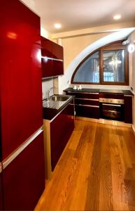 een keuken met rode kasten, een wastafel en een raam bij Bellavita Rooms-Matera Arco 34 in Matera +5 foto's