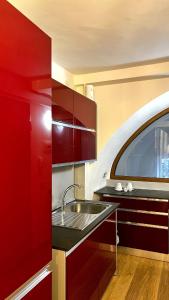 een keuken met rode kasten en een spoelbak bij Bellavita Rooms-Matera Arco 34 in Matera