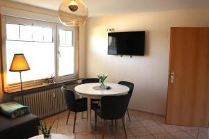 ein Wohnzimmer mit Tisch und Stühlen und einem Fernseher in der Unterkunft Ferienwohnung Borkum in Holtgast