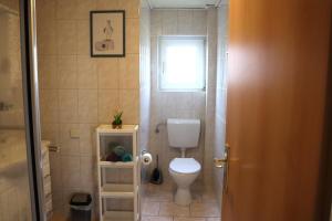 ein kleines Badezimmer mit Toilette und Fenster in der Unterkunft Ferienwohnung Borkum in Holtgast + 11 Fotos