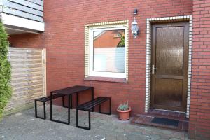 ein Backsteingebäude mit zwei Bänken und einer Tür in der Unterkunft Ferienwohnung Borkum in Holtgast