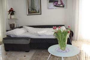 a living room with a bed and a vase of flowers on a table at Appartamento Angelo bianco in Peschiera del Garda