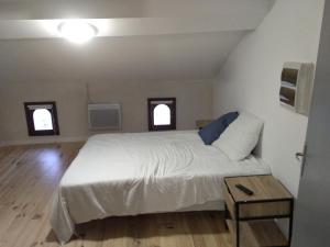 a bedroom with a white bed and two windows at Chez Amandine in Molières