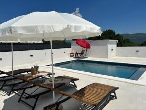 two chairs and an umbrella next to a swimming pool at Torino in Pridraga