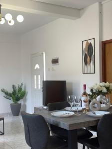 a dining room table with chairs and a bottle of wine at Mythos House in Episkopi Pafou