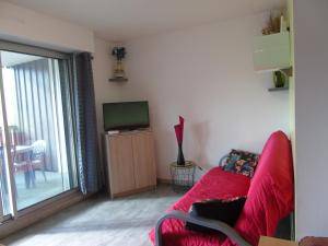 salon z czerwoną kanapą i telewizorem w obiekcie Appartement 4 personnes proche du lac w mieście Gérardmer