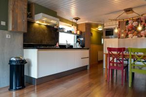 a kitchen with white cabinets and a table and chairs at Chalet Hoenderloo Beuk in Hoenderloo
