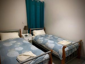 a bedroom with two beds and a blue curtain at City Center Apartments in Mellieħa +3 photos