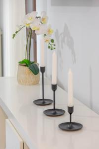 three candles on a counter with flowers in a vase at Casa Amelia lago Maggiore in Maccagno Inferiore