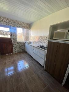 an empty room with a kitchen with a stove at Casa na praia do cassino in Rio Grande