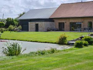 a brick house with a pond in front of it at Chambre d hotes le pigeonnier in Fromelles