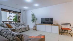 un salon avec un canapé et une télévision à écran plat dans l'établissement Apartamento na Barra da Tijuca a 5 min da praia, à Rio de Janeiro